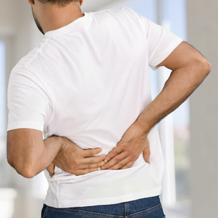 Mann mit Rückenschmerzen und Muskelschmerzen hält sich den unteren Rücken.